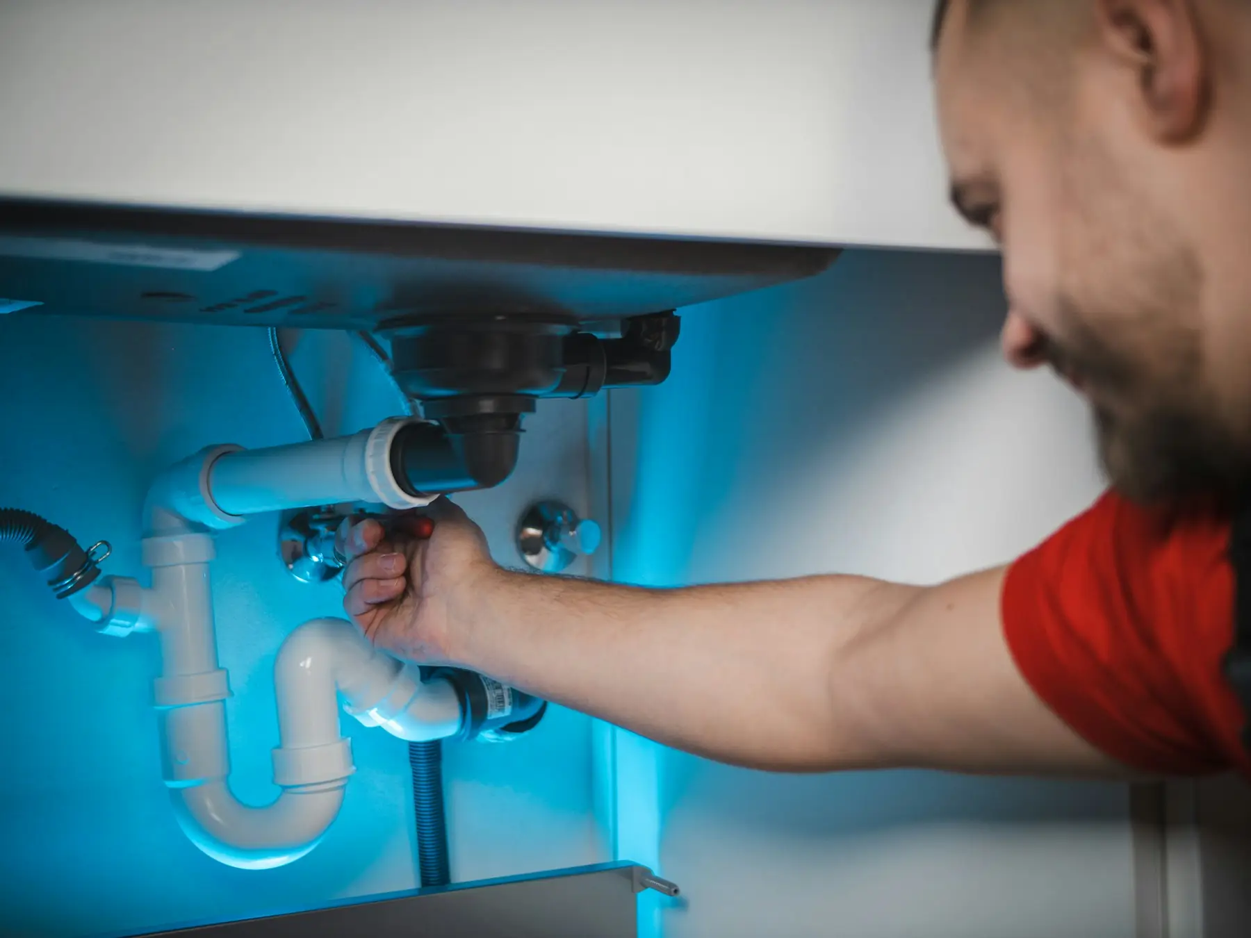 A plumber fixing the pipes under a sink